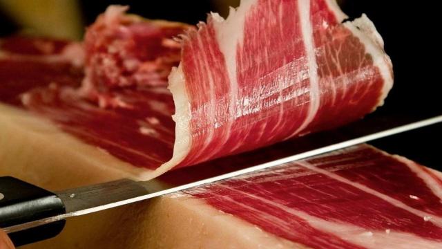 Una persona cortando jamón ibérico.