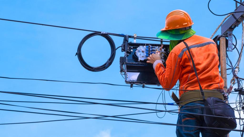 Operario instalando fibra óptica en imagen de archivo.