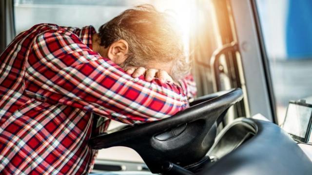 Un hombre recostado sobre el volante del vehículo.