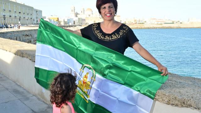 Teresa Rodríguez, junto al mar, con la bandera andaluza y una de sus hijas.