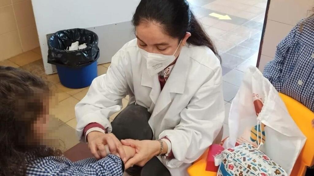 La enfermera Elena Santos junto a una niña del colegio Cristo Rey, en Valladolid