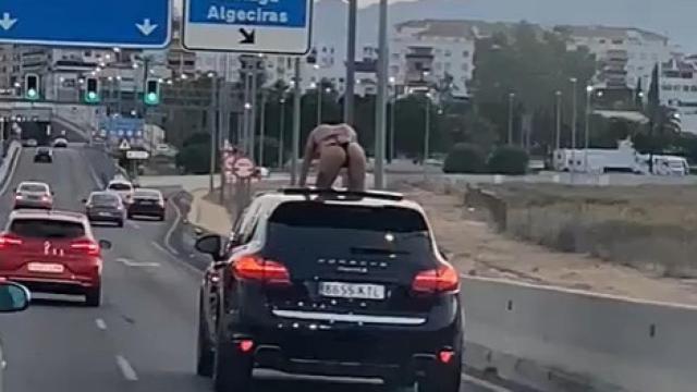 Una mujer sobre un coche en plena autovía.