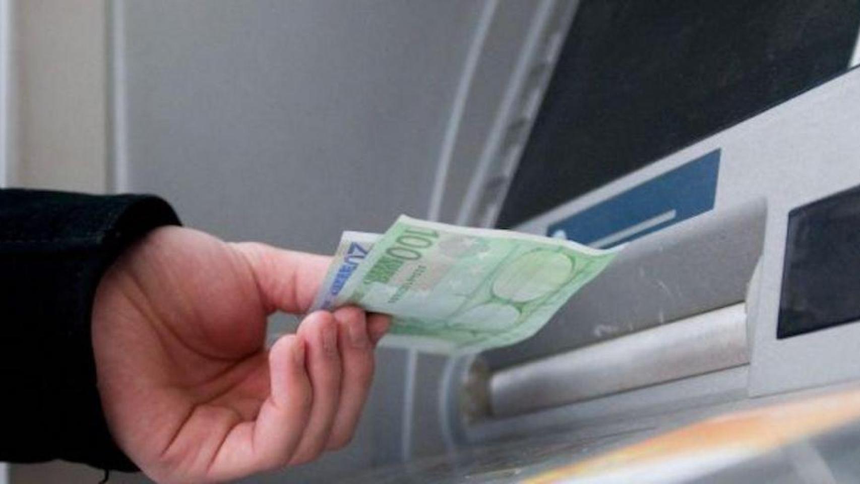 Un hombre saca dinero de un cajero automático.