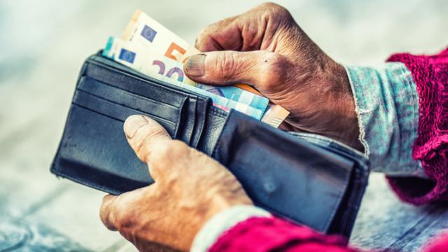 Un jubilado saca dinero de su monedero