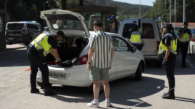 Agentes de la Policía Nacional, este martes, revisando a fondo el coche de un conductor.
