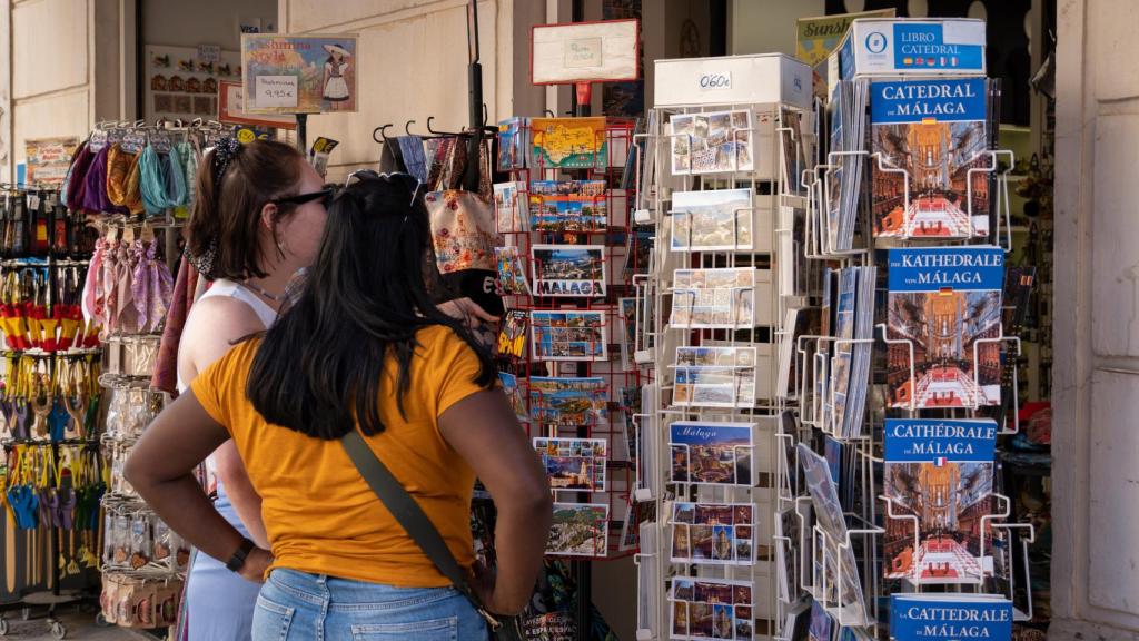 Unos turistas miran tranquilamente unas postales.
