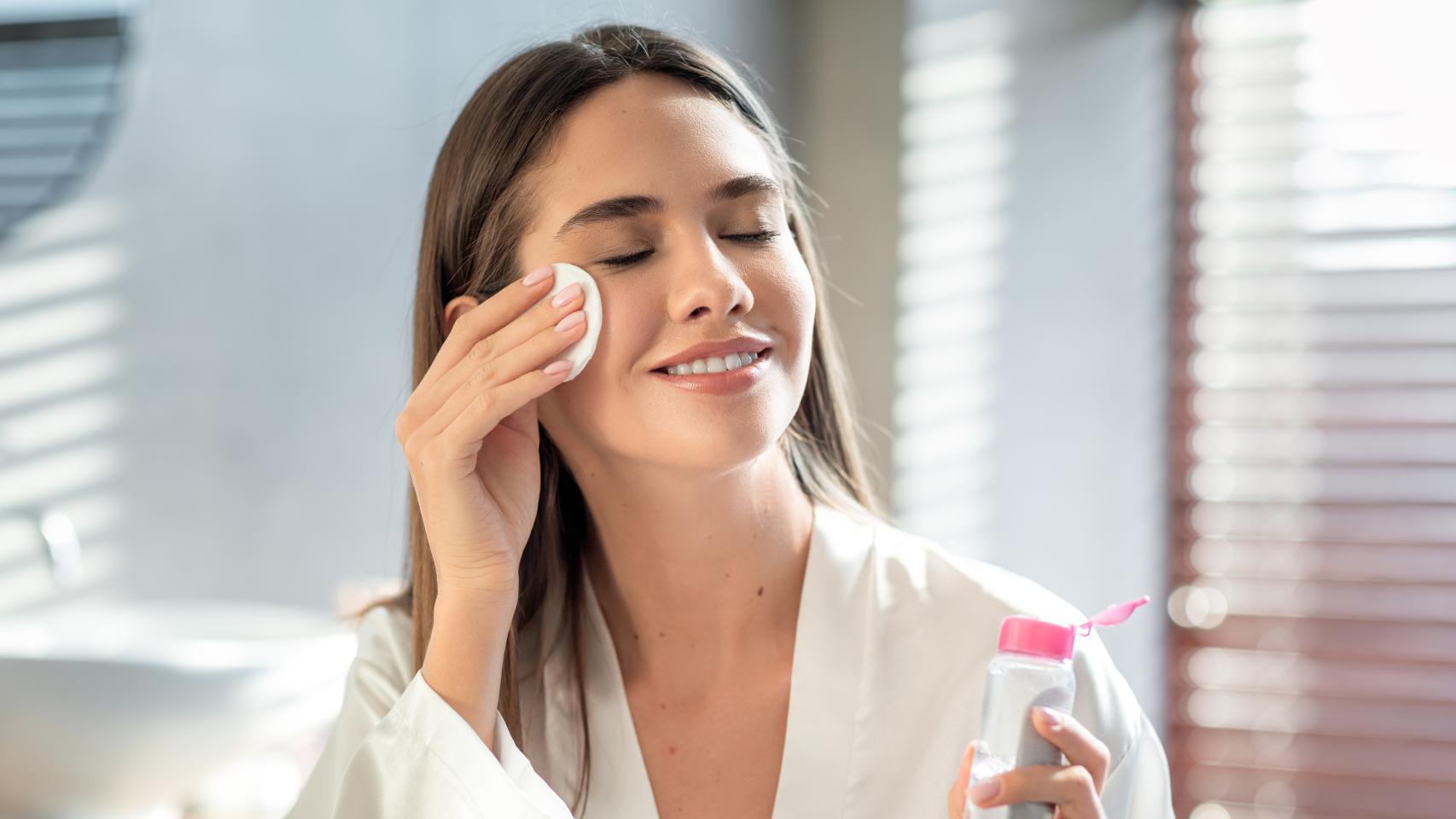Una mujer se limpia la cara con agua micelar.