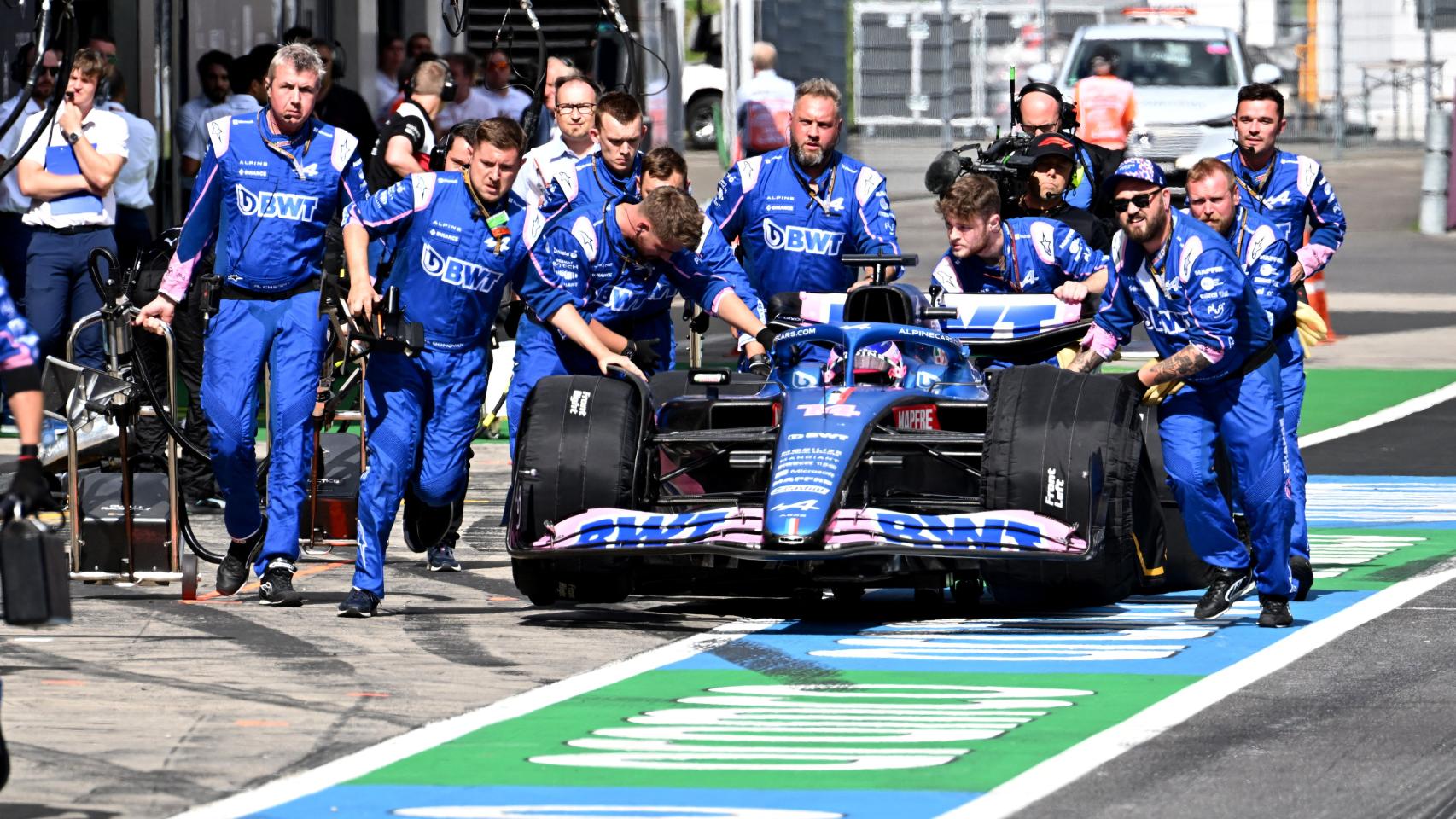 Los mecánicos de Alpine empujan el coche de Fernando Alonso por el pitlane