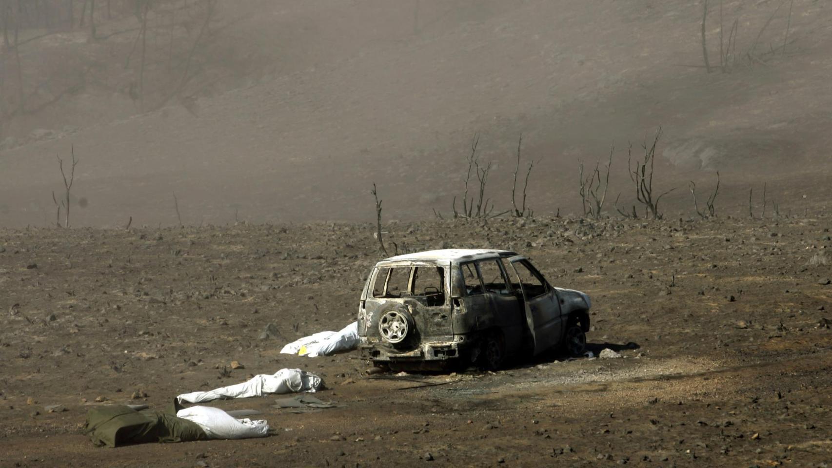 Varios cadáveres junto a uno de los vehículos calcinados.
