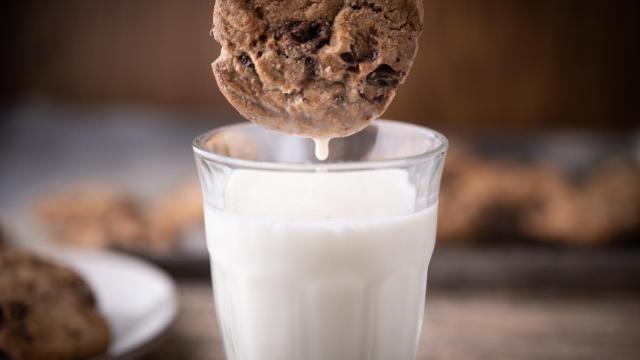 Una galleta siendo sumergida en un vaso de agua.
