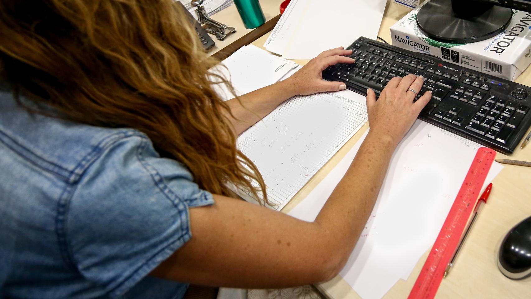 Una mujer escribe en el teclado de su ordenador