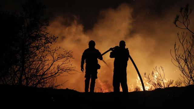 Dos bomberos trabajan en las labores de extinción de un fuego.