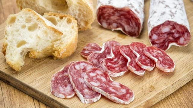 Una barra de fuet cortada en pequeñas lonchas.