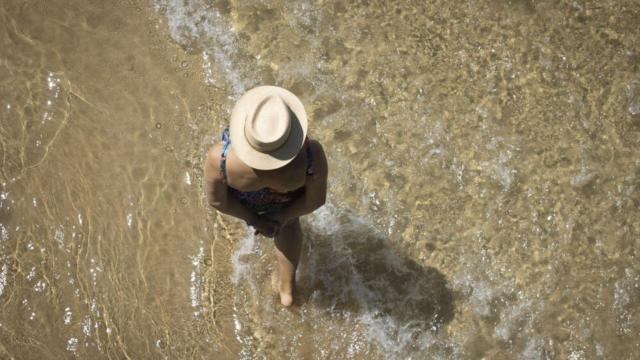 Una mujer mayor paseando por una playa, en imagen de archivo.
