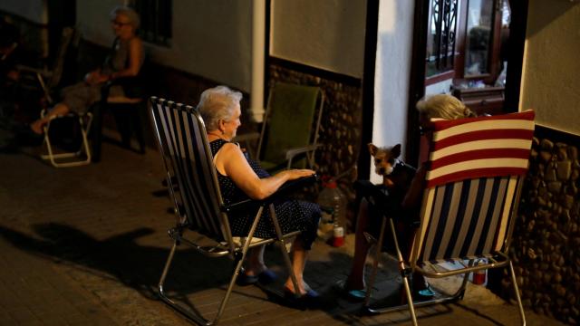 Tres mujeres toman el aire para evitar el calor dentro de sus casas, en Cádiz.