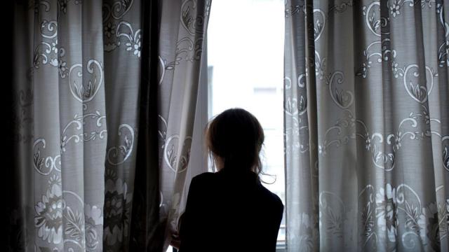 Una persona mira a través de una ventana, en imagen de archivo.