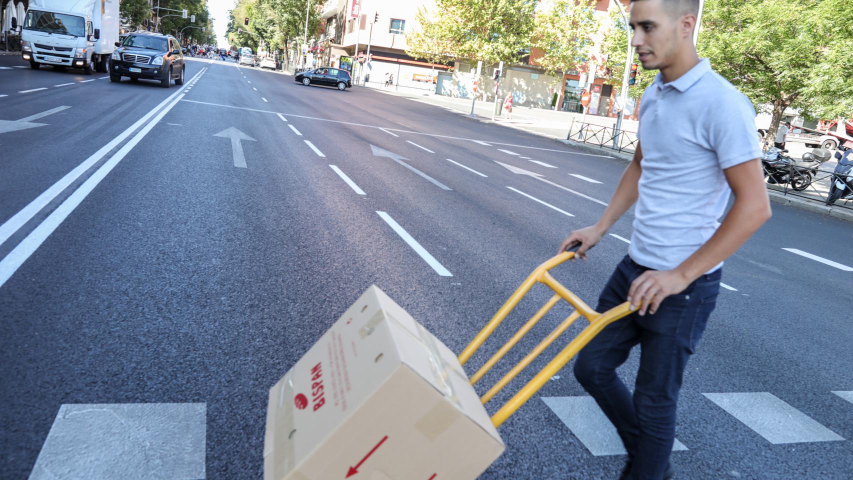 Un hombre traslada una caja con material en una carretilla