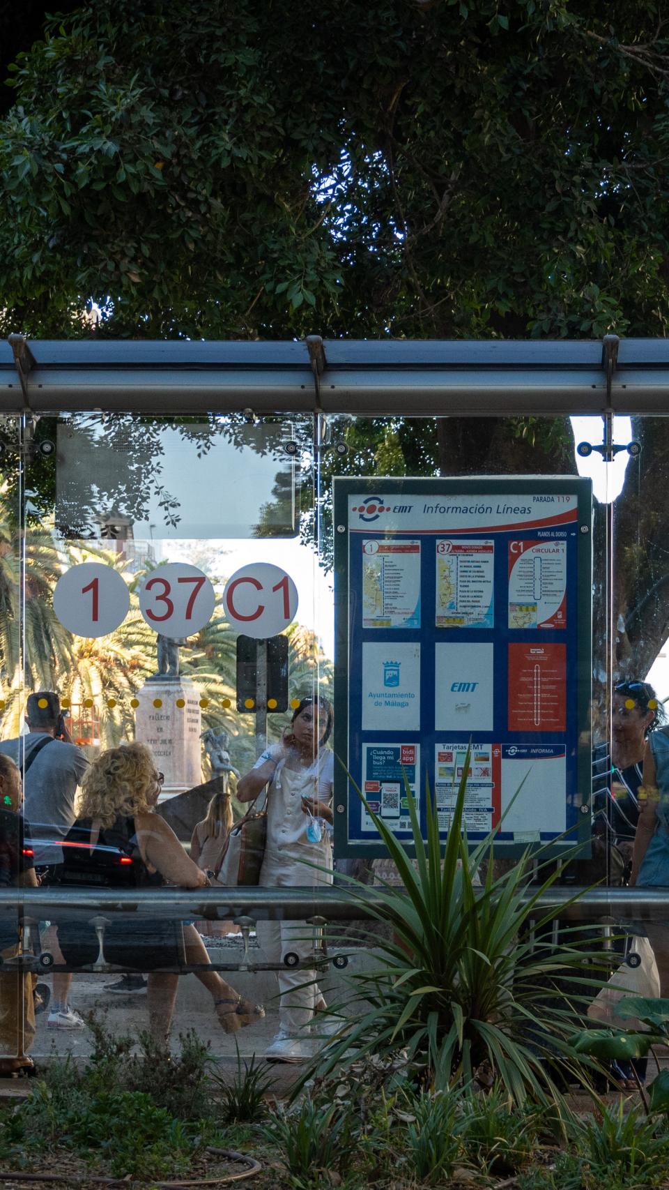 Un grupo de personas espera al autobús en una parada de la EMT en la Alameda de Málaga.