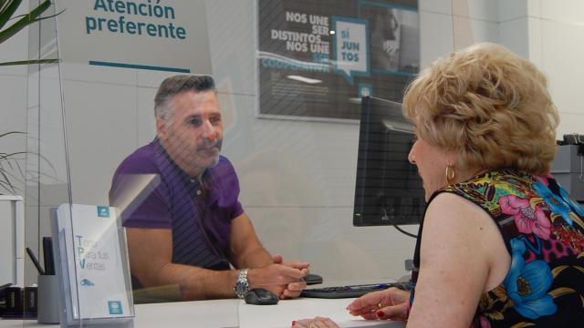Un trabajador de Cajamar atiende a una clienta en una de sus oficinas bancarias