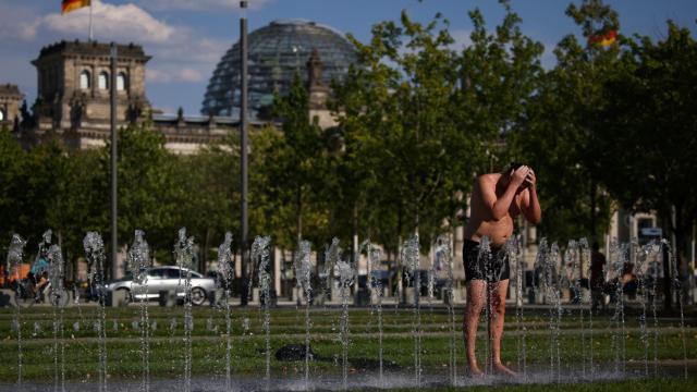 Un hombre se refresca frente al edificio de la cámara baja alemana durante la ola de calor.