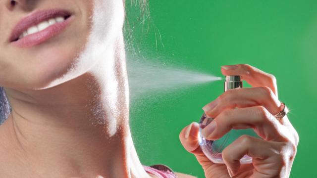 Mujer perfumándose el cuello.