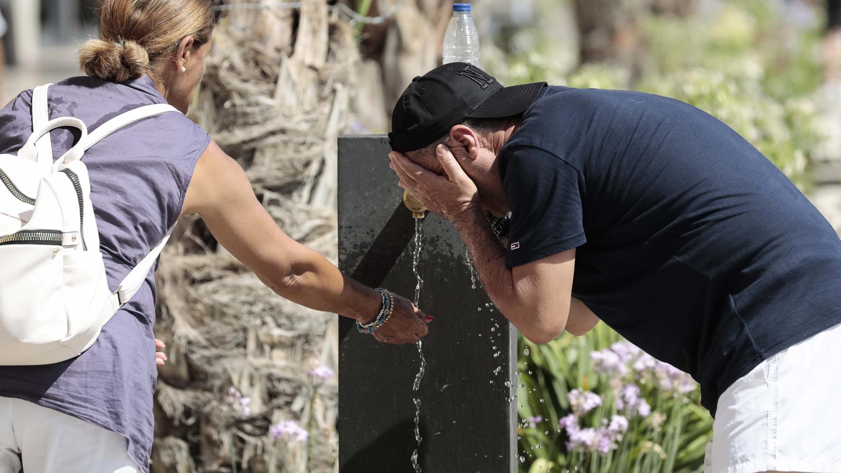 Dos personas se refrescan en una fuente del centro de Valencia.