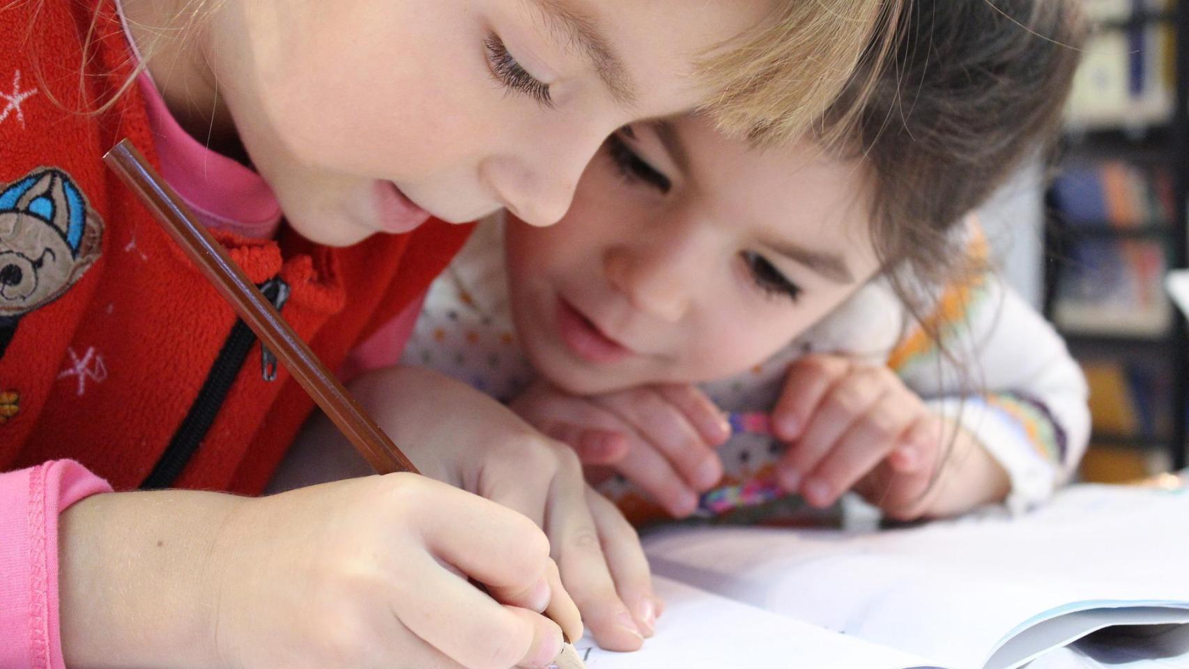 Dos niños dibujando en un cuaderno.