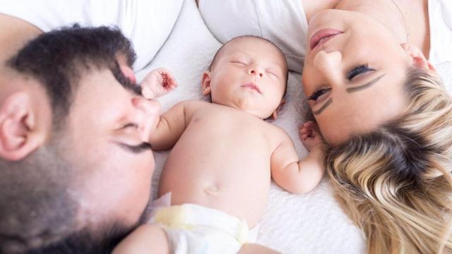Una pareja junto a un bebé.