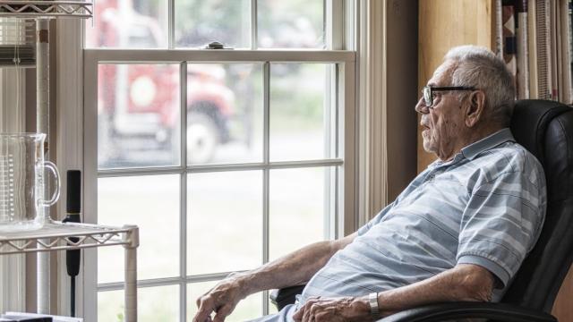 Un anciano mirando a través de una ventana.
