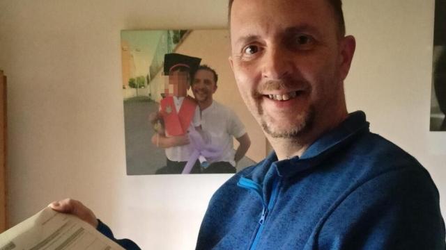 Javier Avellaneda posa con documentación y con la foto junto a su hijo al fondo