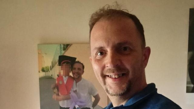 Javier Avellaneda posa con documentación y con la foto junto a su hijo al fondo