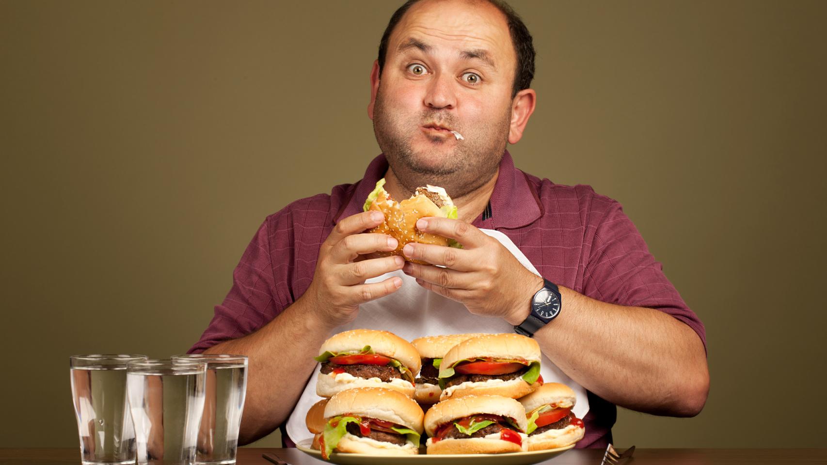 Un señor devorando unas cuantas hamburguesas.