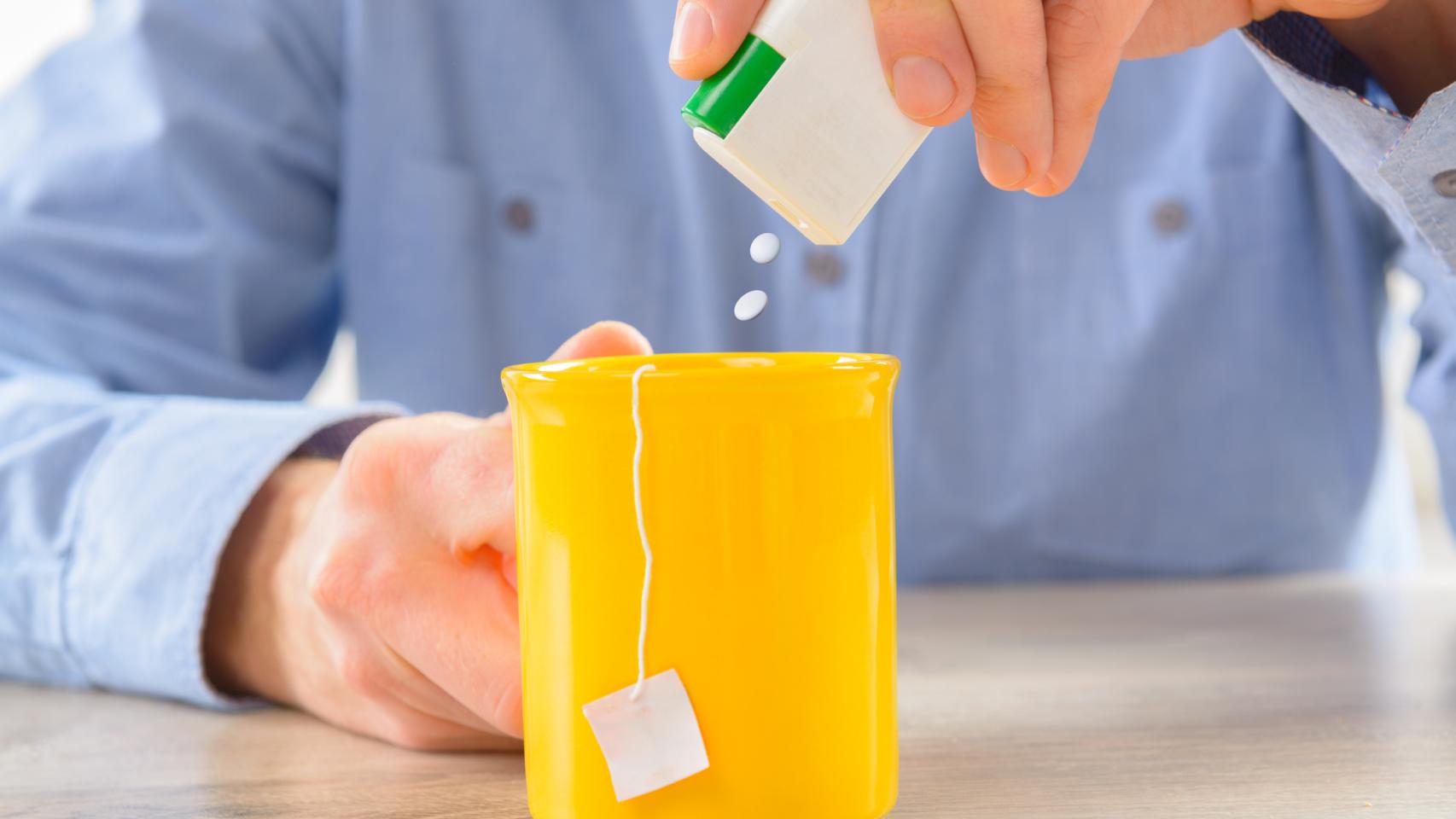 Un señor echando sacarina en una tacita de té.