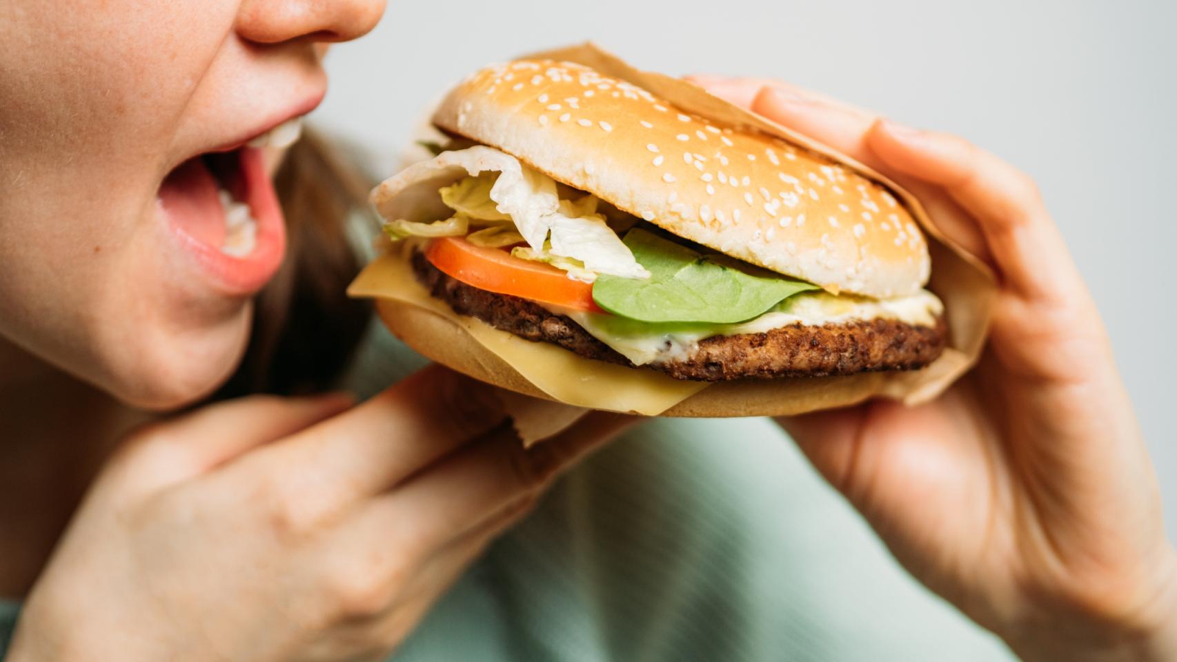 Una joven comiéndose una hamburguesa.