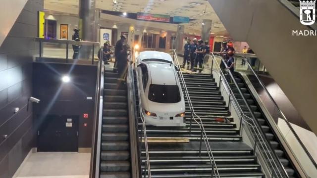 Bomberos del Ayuntamiento de Madrid retiran el coche encajado en las escaleras del intercambiador de Plaza Elíptica.