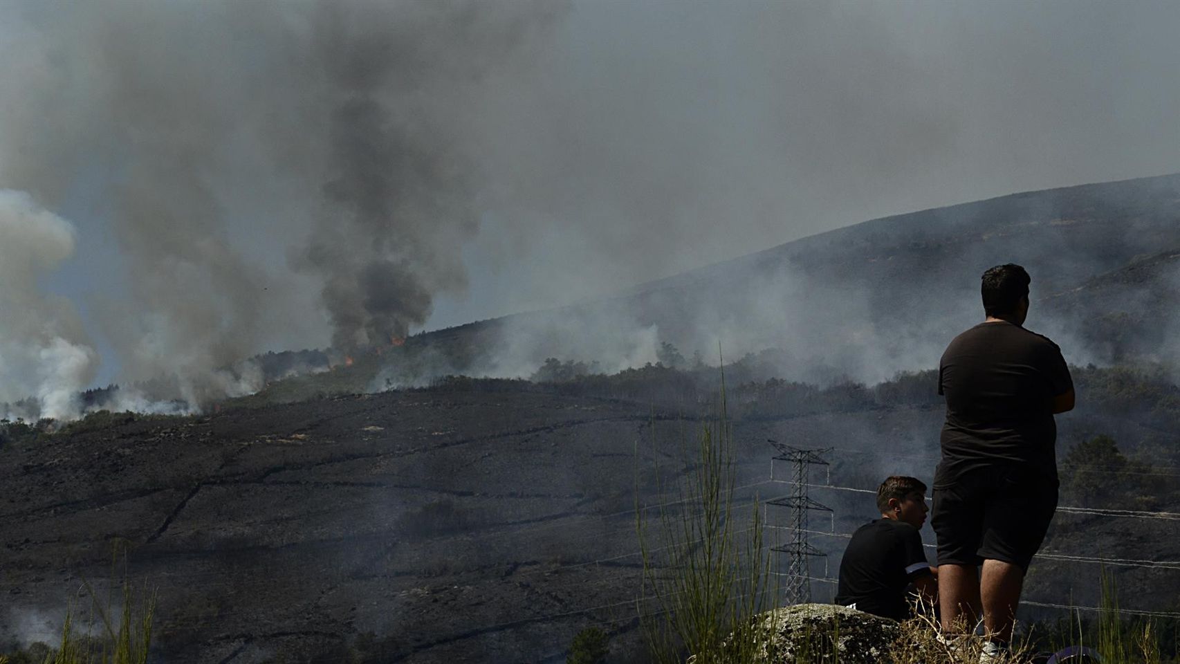 Dos personas de Grou observan el incendio forestal en la Serra do Leboreiro, en Senderiz, en el parque natural de Baixa Limia e Serra do Xurés.