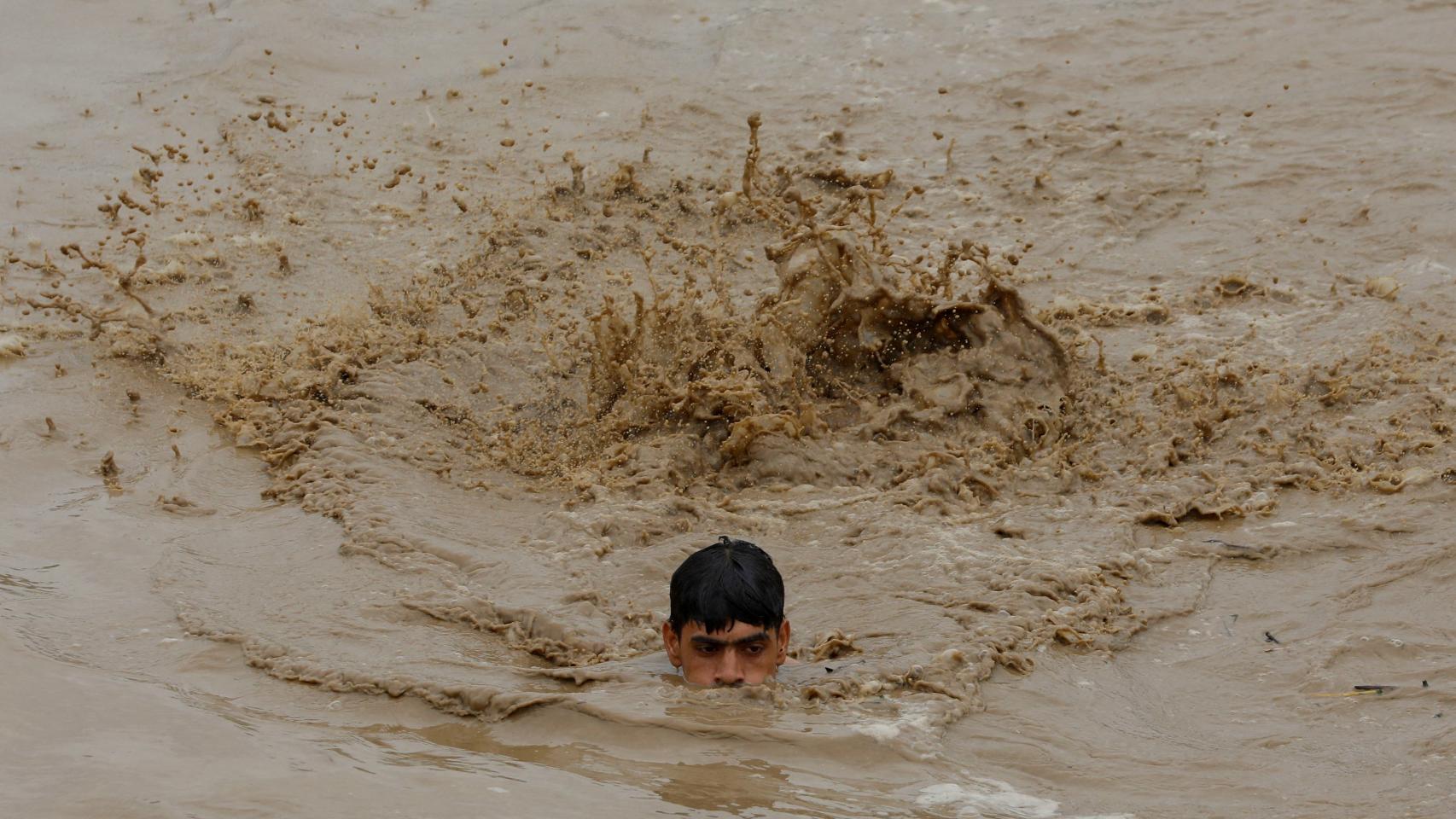 Un hombre nada para salvar la vida en las inundaciones en la localidad de Charsadda, en Pakistán.