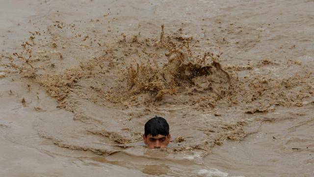Un hombre nada para salvar la vida en las inundaciones en la localidad de Charsadda, en Pakistán.