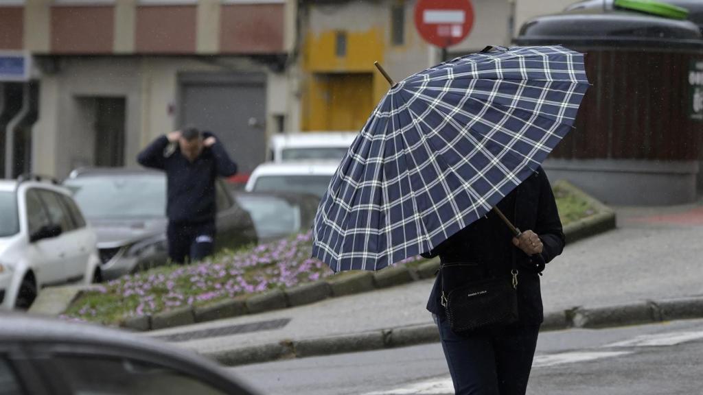 Un ciudadano se protege ante una fuerte racha de viento