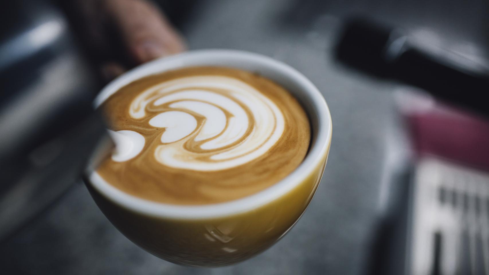Un barista prepara un café con leche.