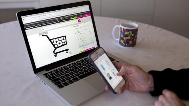 Una persona realizando compras online con su teléfono móvil y ordenador