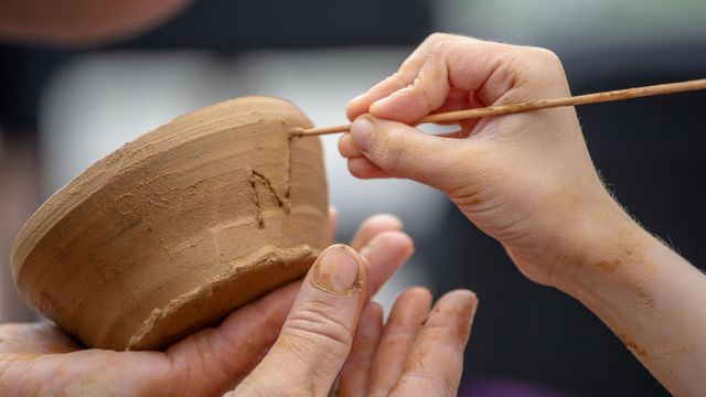 Niño haciendo un patrón en un tazón de arcilla.
