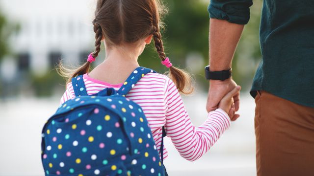 Imagen de archivo de un padre y su hija de camino al colegio.