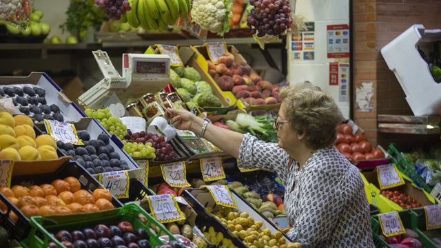 Una mujer compra en uno de los puestos del mercado de abastos de Triana, Sevilla.