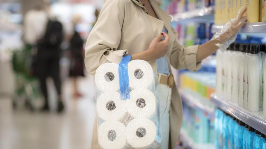 Una mujer compra un paquete de rollos de papel higiénico.