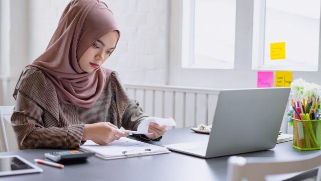 Una mujer con abaya trabajando.