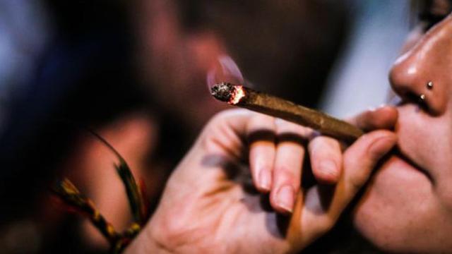 Una persona le da una calada a un porro que parece una antorcha.