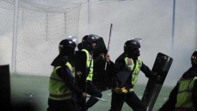 Los policias cargan durante el partido ante la multitud en el terreno de juego.