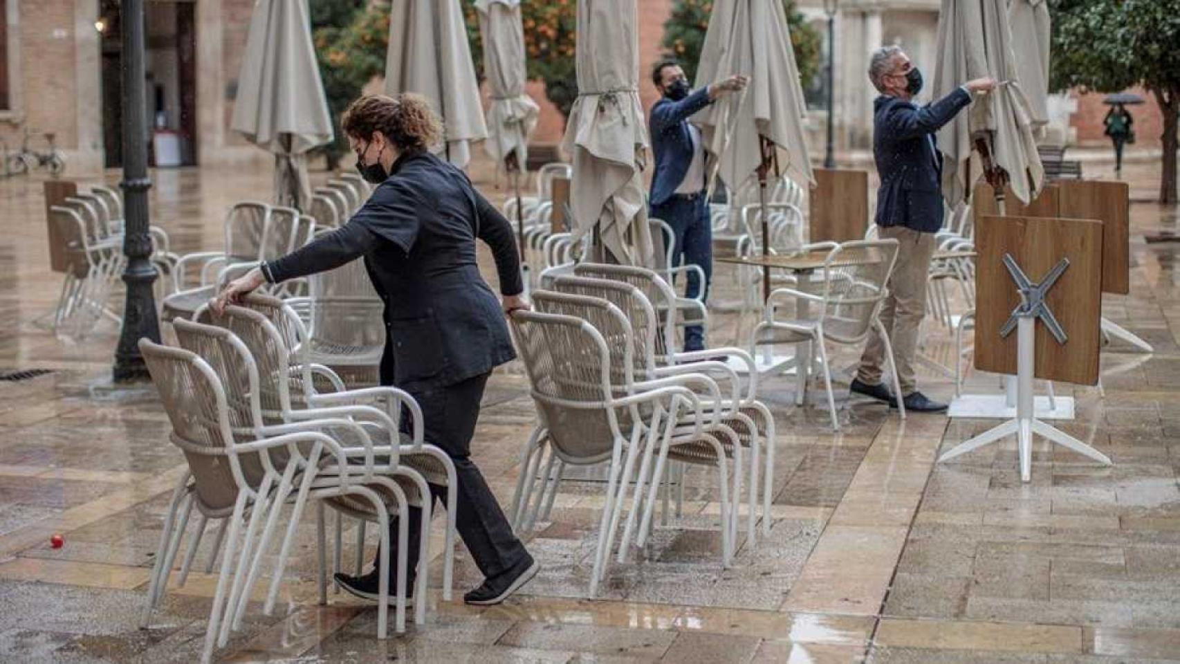 Una camarera recoge unas sillas.