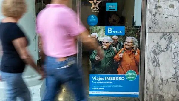 Dos personas pasan por delante de una oficina en Valencia que oferta viajes del Imserso.